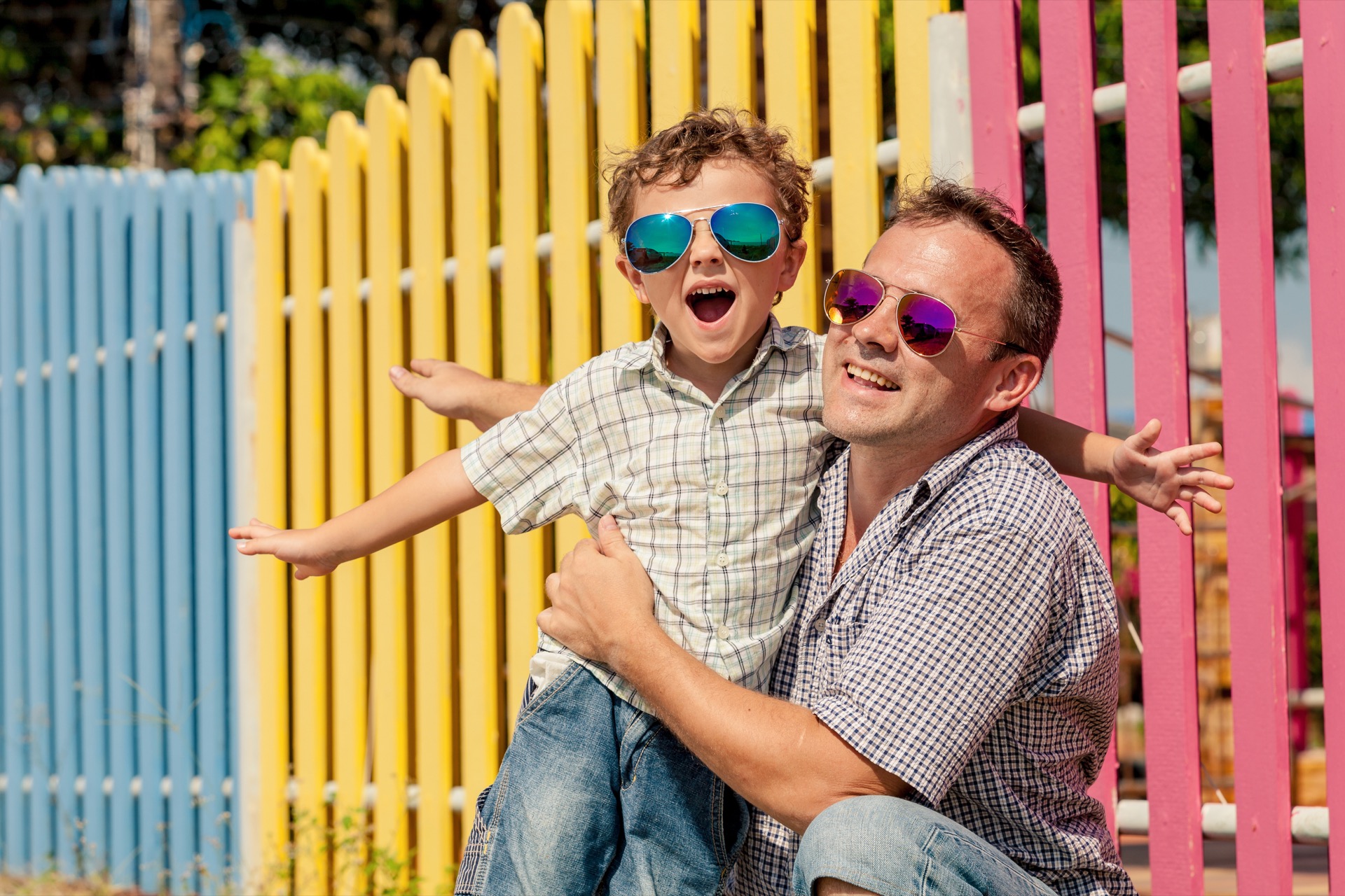 Young boy wearing children's sunglasses beside dad
