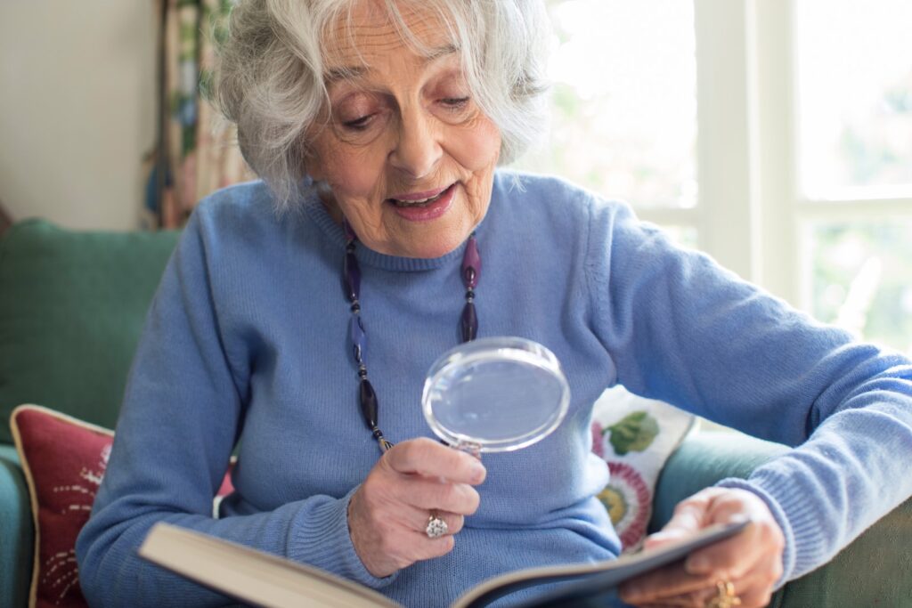 Senior woman using magnifying glass to read