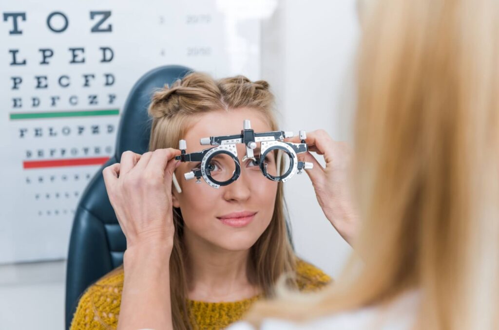 Optometrist performing a vision test with an eye chart in the background