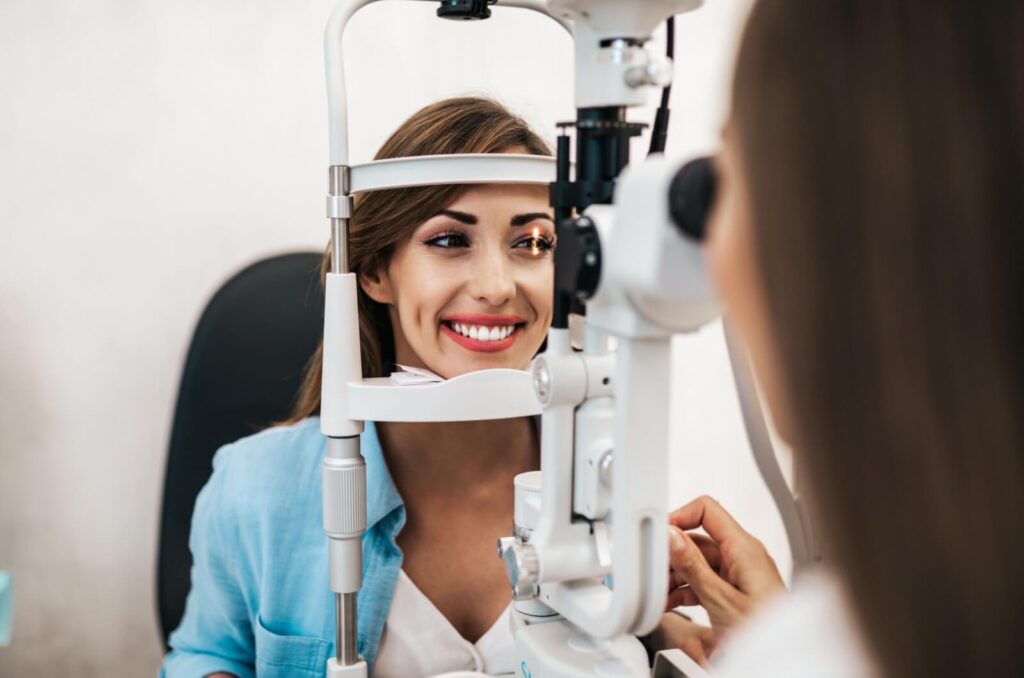 Smiling woman undergoing an eye exam with advanced equipment