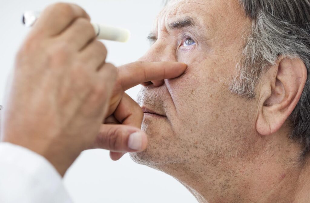 A healthcare provider examining an individual's eye using a penlight, focusing on the signs of eye health issues.