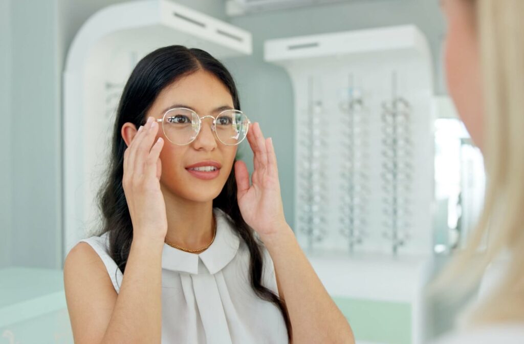 An optometry patient adjusting their new glasses after an eye exam and smiling with their new prescription.