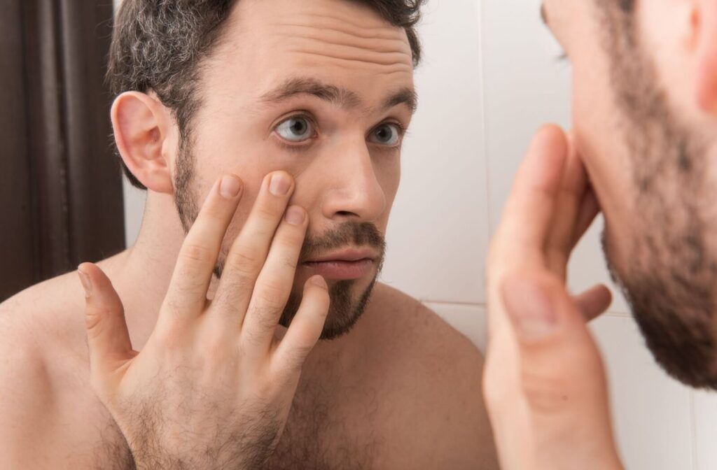 A person pulls down their eyelid to inspect their eye for signs of infection.