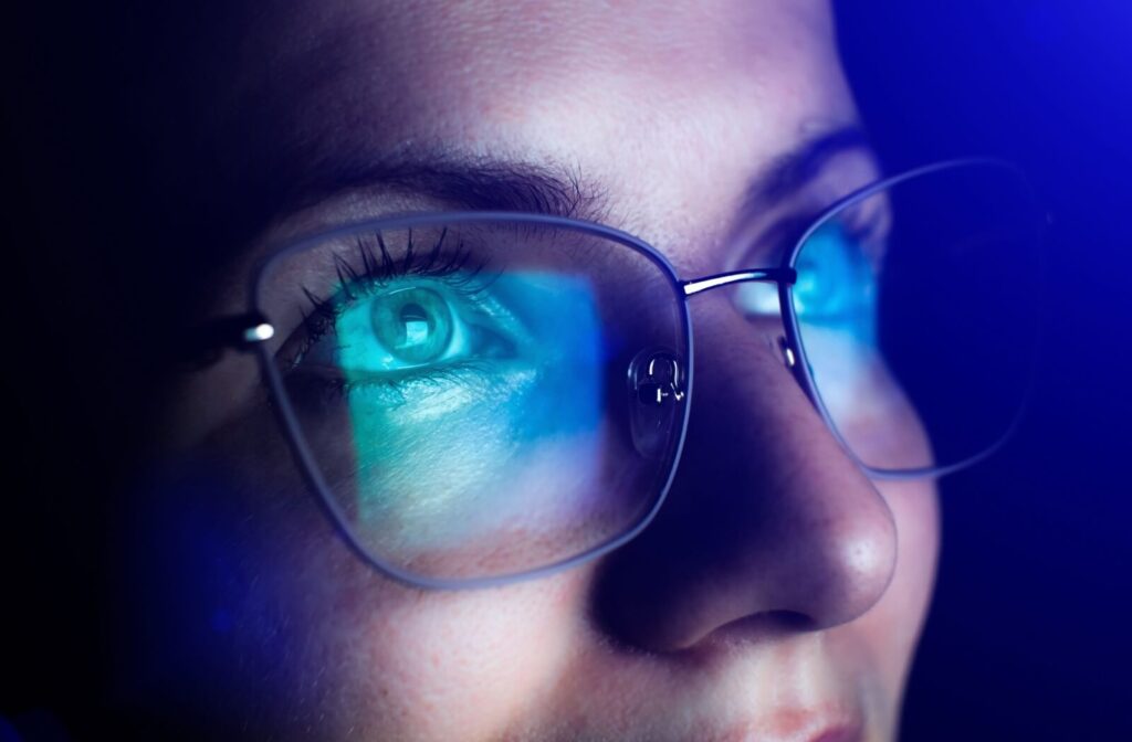Close-up of blue light glasses with visible blue light reflecting off the lenses.