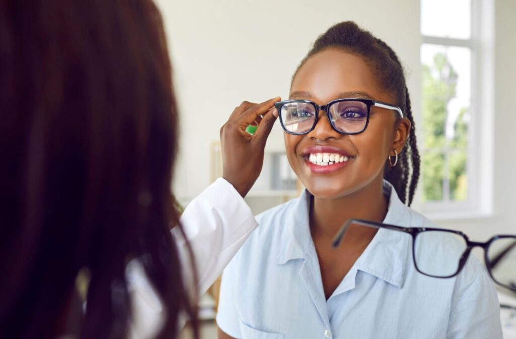 Patient smiling while being fitted for blue light glasses at an optometry clinic.