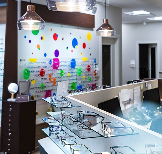 An optometrist space showing multiple eyeglass frames on modern counters
